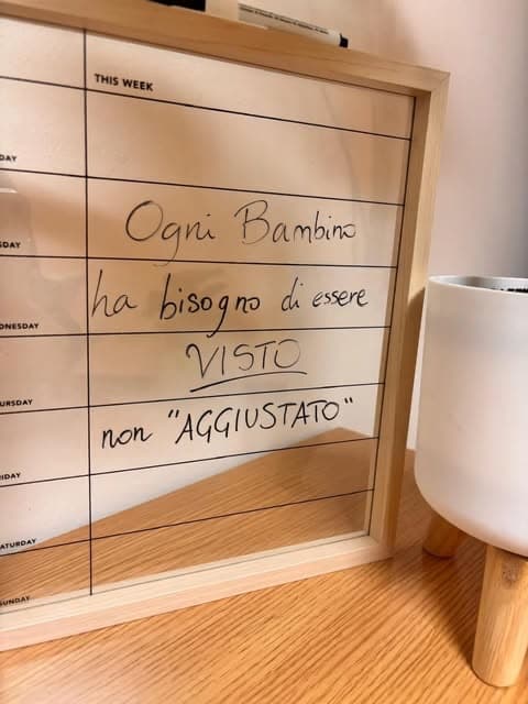 Lavagnetta appesa nello studio con la scritta a mano: ogni bambino ha bisogno di essere visto, non aggiustato